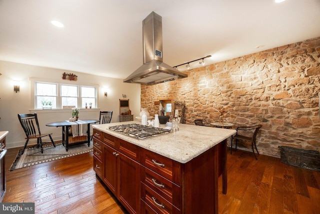 kitchen featuring light stone countertops, track lighting, a kitchen island, island exhaust hood, and stainless steel gas cooktop