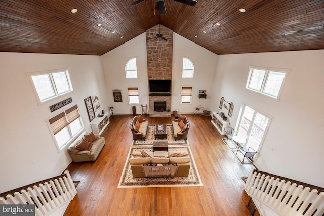 living room featuring wood-type flooring, a fireplace, ceiling fan, high vaulted ceiling, and wooden ceiling