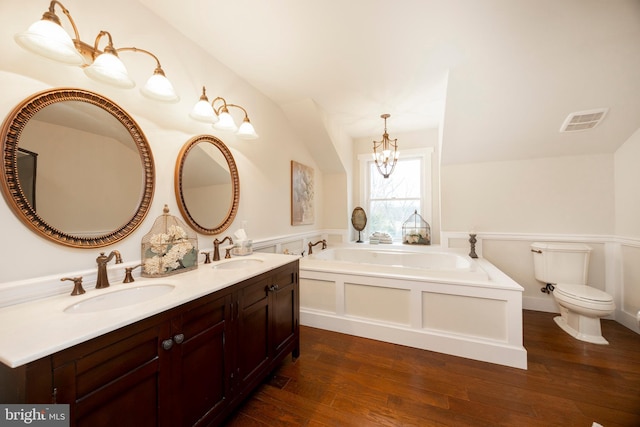 bathroom with toilet, a bath, hardwood / wood-style floors, and vanity