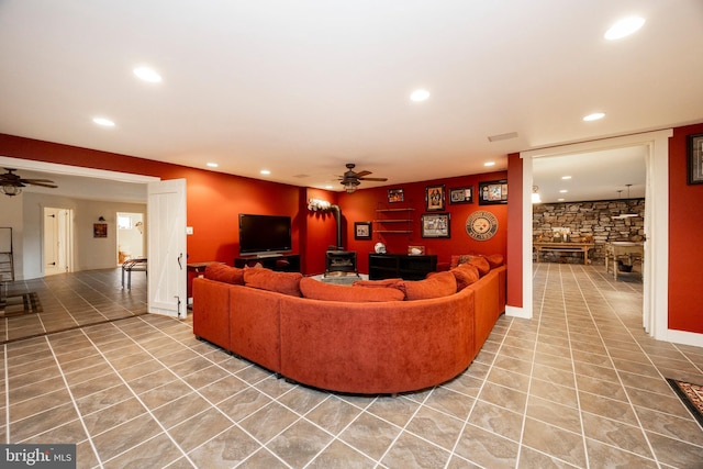 living room featuring ceiling fan and a wood stove