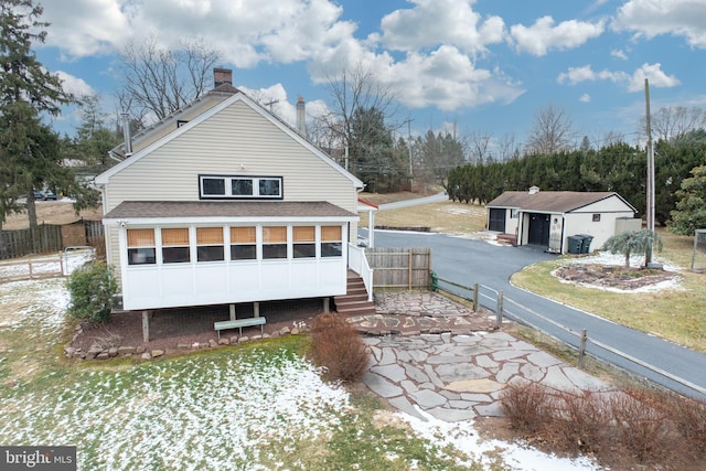 view of home's exterior featuring a garage, an outbuilding, and a sunroom