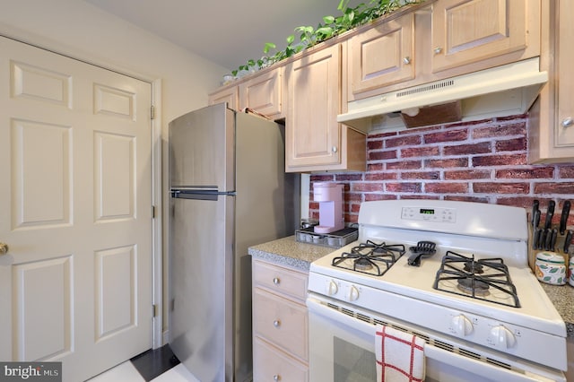 kitchen with light countertops, white gas range oven, freestanding refrigerator, and under cabinet range hood