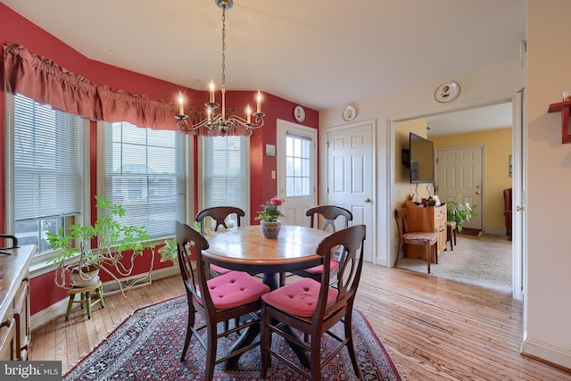 dining room with a chandelier, light wood-style flooring, and baseboards