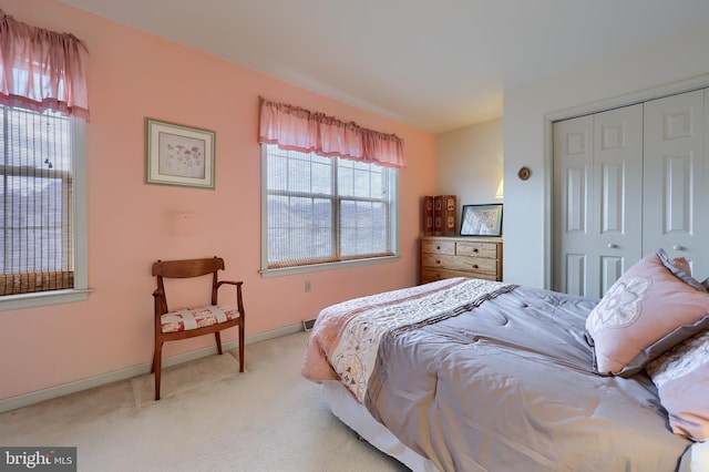 bedroom featuring baseboards, a closet, and light colored carpet