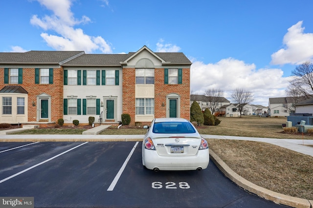 view of front of property featuring uncovered parking, a residential view, and brick siding