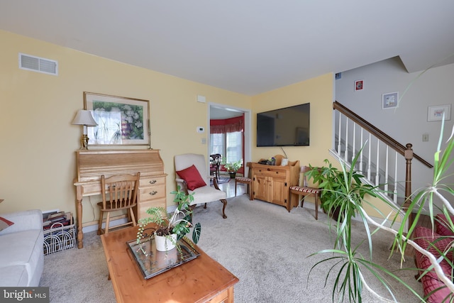 carpeted living room featuring visible vents and stairs