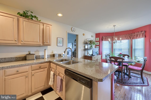 kitchen with a peninsula, light brown cabinetry, stainless steel dishwasher, a chandelier, and a sink