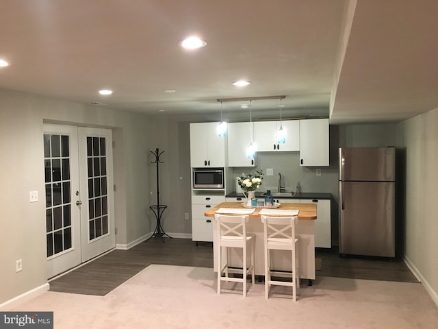 kitchen featuring white cabinets, a kitchen breakfast bar, a center island, stainless steel appliances, and french doors