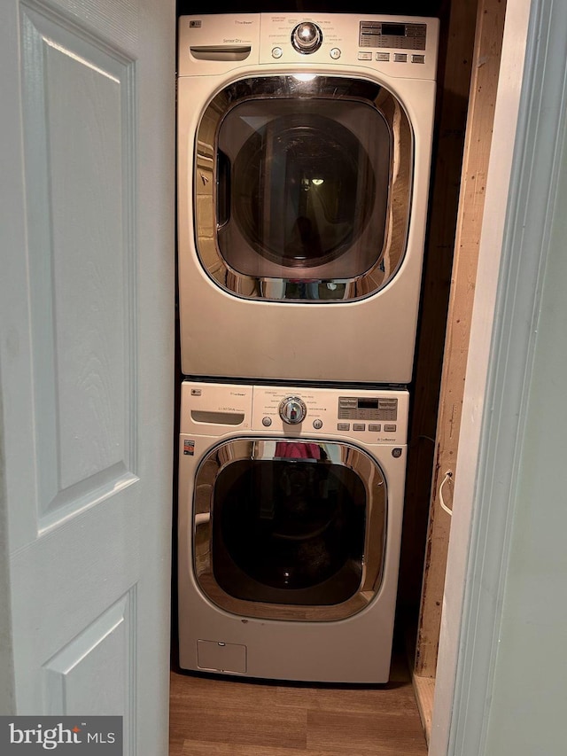 laundry room featuring stacked washer / drying machine and light hardwood / wood-style floors