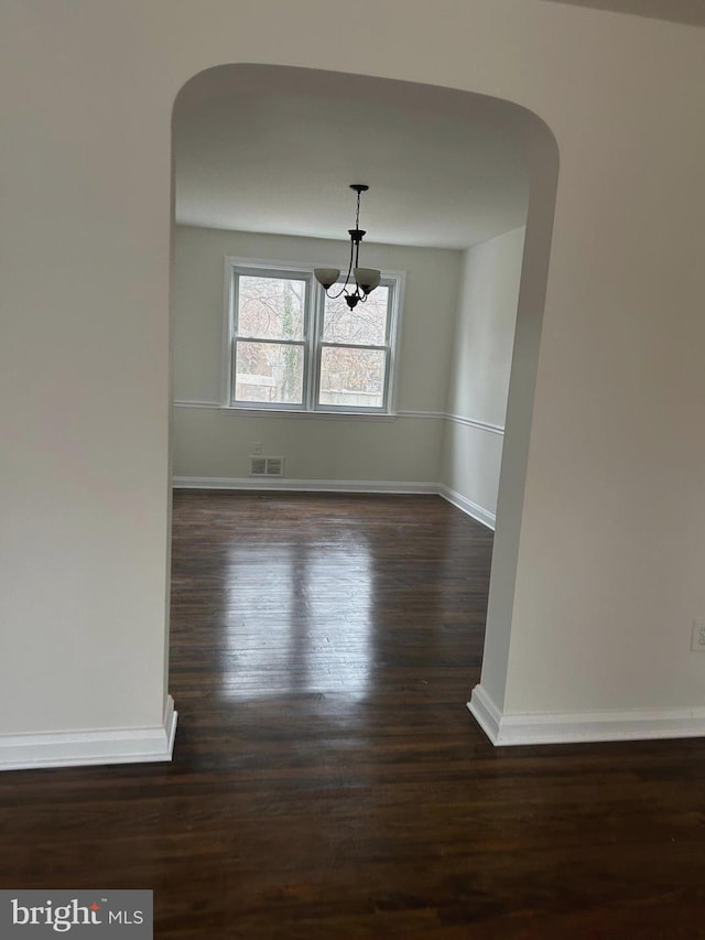 unfurnished room with dark hardwood / wood-style floors and a chandelier