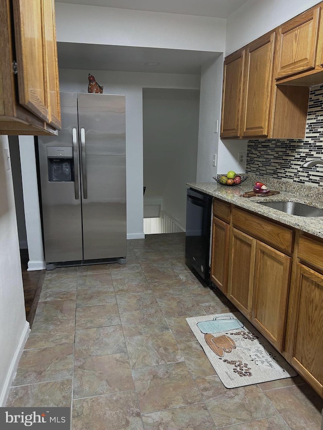 kitchen with dishwasher, sink, stainless steel fridge, decorative backsplash, and light stone counters