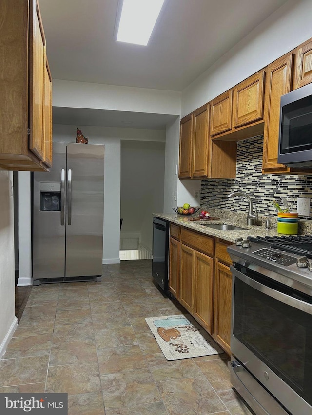 kitchen featuring stainless steel appliances, tasteful backsplash, light stone countertops, and sink