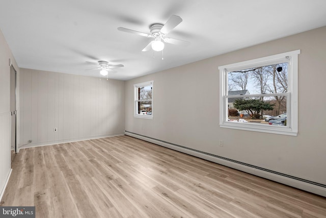 empty room with baseboard heating, a healthy amount of sunlight, and light wood-type flooring