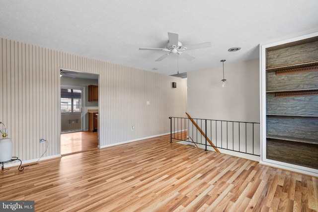 spare room with ceiling fan, a textured ceiling, and light wood-type flooring