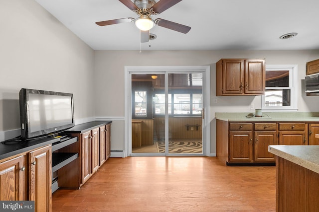 kitchen with ceiling fan, a baseboard radiator, and light hardwood / wood-style floors