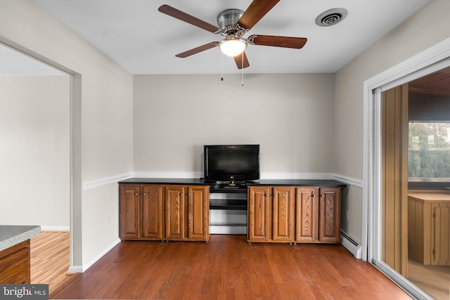 interior space featuring dark hardwood / wood-style floors, ceiling fan, and baseboard heating