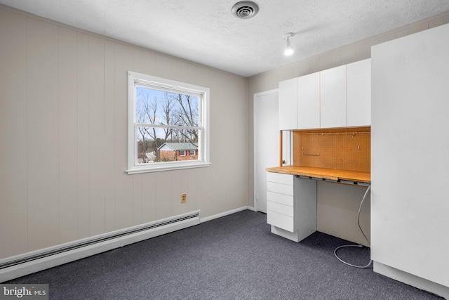 unfurnished office with dark carpet, a textured ceiling, and a baseboard heating unit