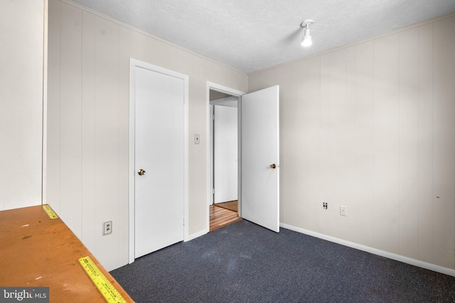 unfurnished bedroom with dark colored carpet and a textured ceiling