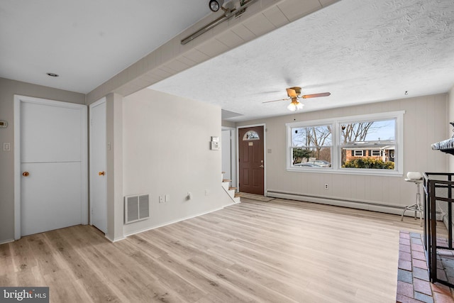 unfurnished living room featuring baseboard heating, ceiling fan, light hardwood / wood-style floors, and a textured ceiling