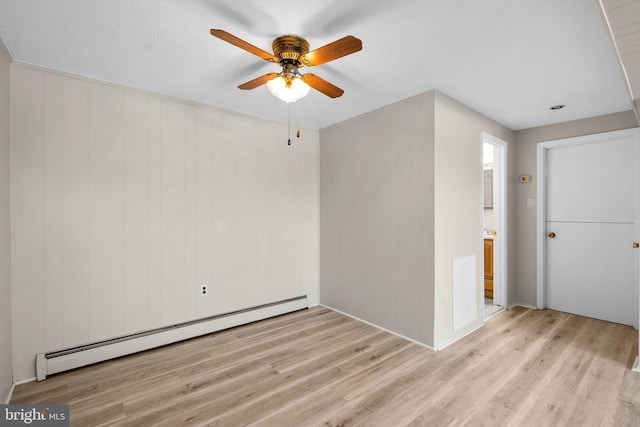 unfurnished room featuring baseboard heating, wooden walls, and light hardwood / wood-style floors