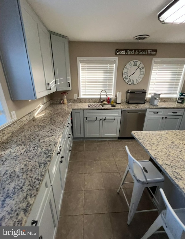 kitchen with a wealth of natural light, sink, stainless steel dishwasher, and tile patterned floors