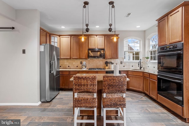 kitchen featuring decorative light fixtures, dark hardwood / wood-style flooring, black appliances, a breakfast bar, and sink