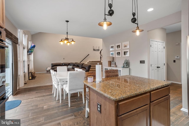 kitchen featuring light stone countertops, dark wood-type flooring, pendant lighting, and a kitchen island