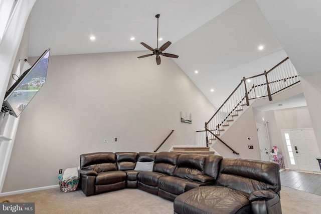 carpeted living room featuring ceiling fan and a towering ceiling