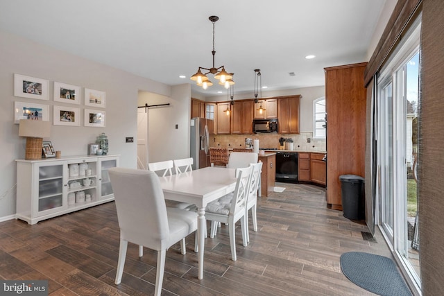 dining room with an inviting chandelier, dark hardwood / wood-style flooring, and a barn door