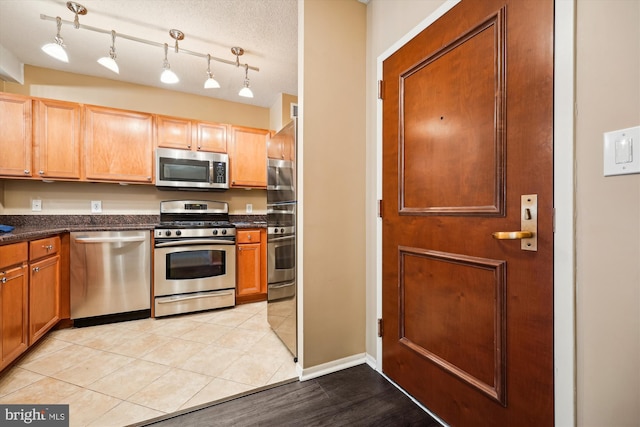 kitchen with a textured ceiling, light tile patterned floors, and stainless steel appliances