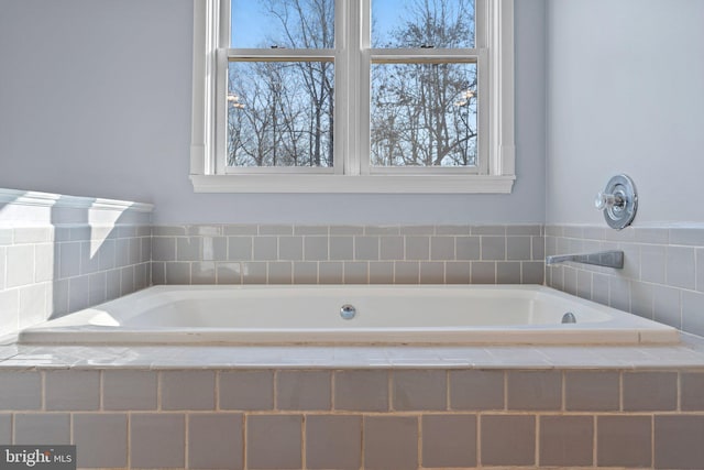 bathroom with a relaxing tiled tub and plenty of natural light