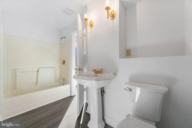 bathroom with shower / washtub combination, hardwood / wood-style floors, and toilet