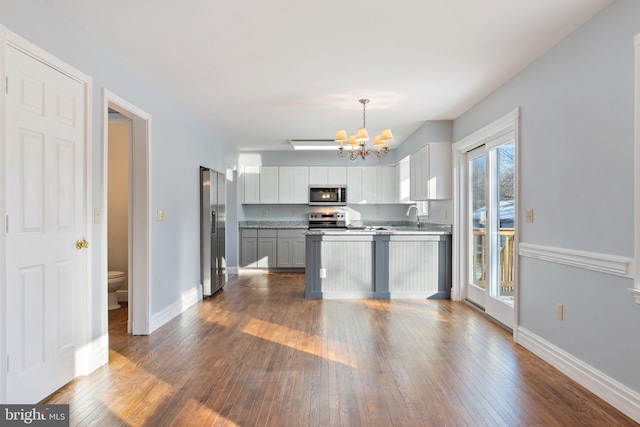 kitchen featuring pendant lighting, sink, dark wood-type flooring, stainless steel appliances, and a chandelier