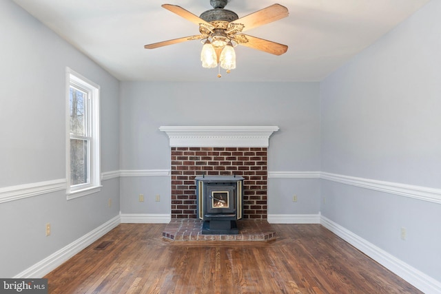 unfurnished living room with ceiling fan, dark hardwood / wood-style flooring, and a wood stove