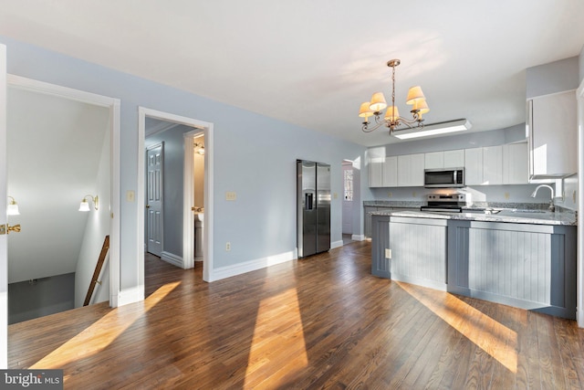 kitchen with appliances with stainless steel finishes, pendant lighting, white cabinetry, sink, and dark wood-type flooring