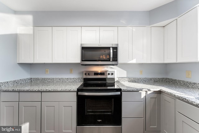 kitchen featuring white cabinetry, light stone counters, and appliances with stainless steel finishes