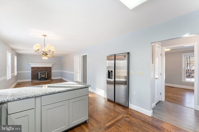 kitchen featuring gray cabinets, light stone countertops, a healthy amount of sunlight, and stainless steel fridge with ice dispenser