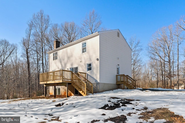 snow covered back of property with a deck