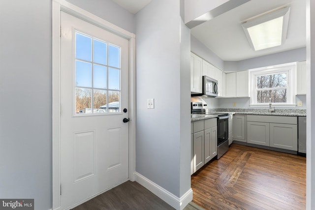 kitchen featuring dark wood-type flooring, sink, appliances with stainless steel finishes, gray cabinets, and light stone countertops