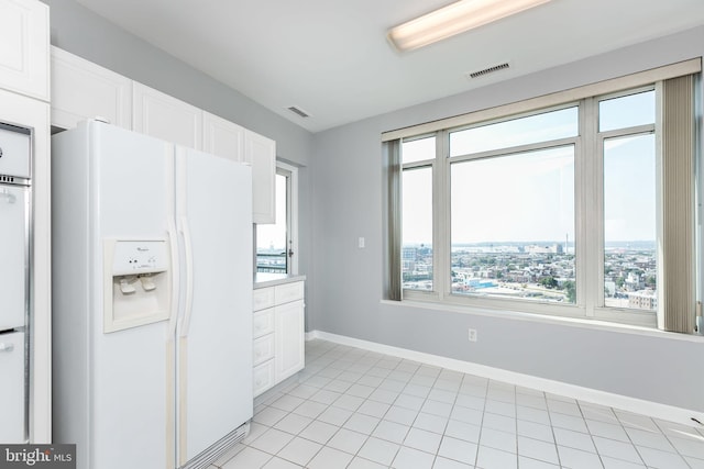 kitchen with light tile patterned floors, white cabinetry, and white refrigerator with ice dispenser