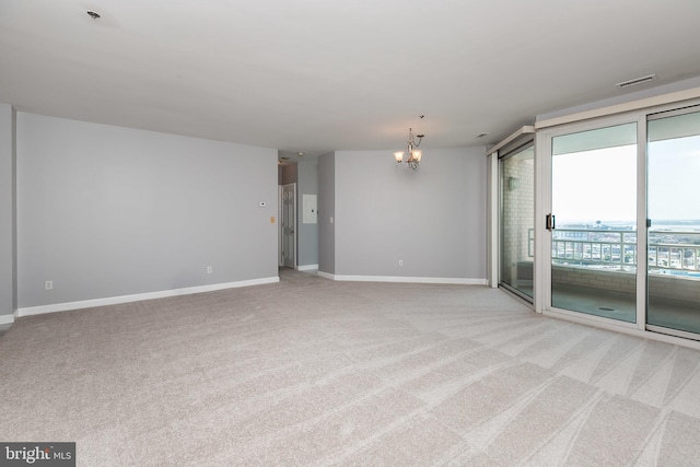 spare room featuring light carpet and an inviting chandelier