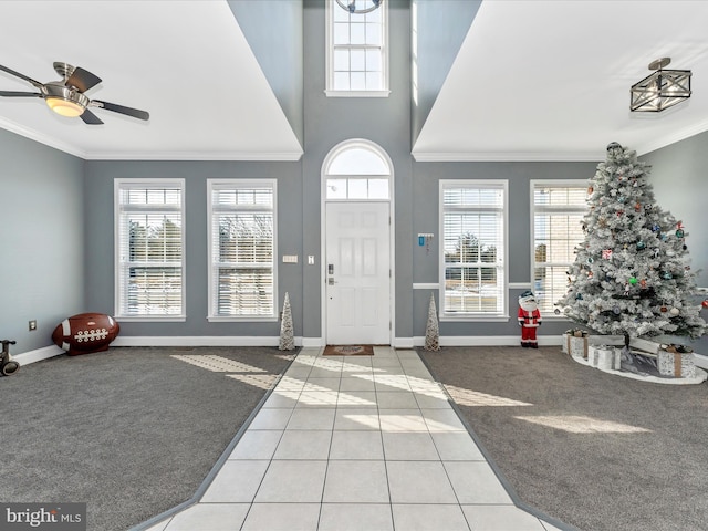 carpeted foyer with ceiling fan, a wealth of natural light, and crown molding