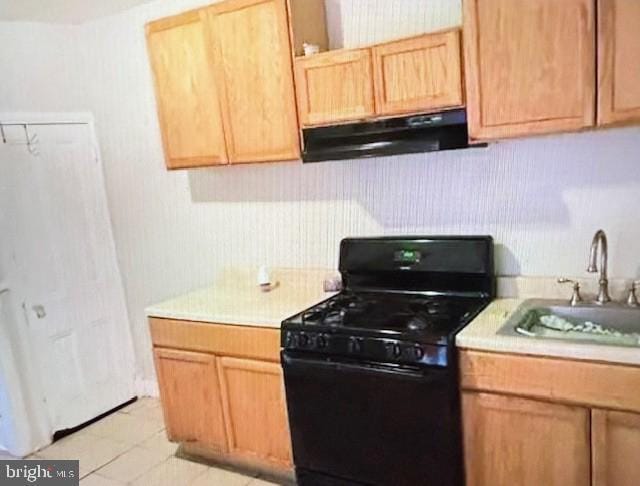 kitchen with black gas range, light tile patterned floors, ventilation hood, light brown cabinetry, and sink