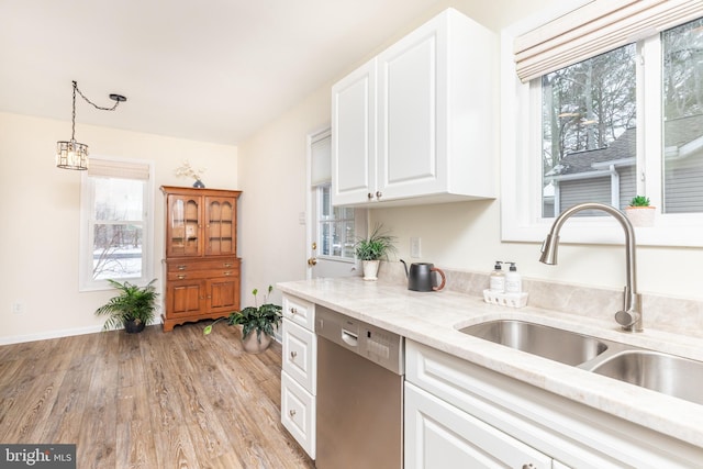 kitchen with sink, light hardwood / wood-style flooring, white cabinetry, decorative light fixtures, and stainless steel dishwasher