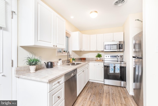 kitchen with white cabinetry, stainless steel appliances, light hardwood / wood-style floors, and sink