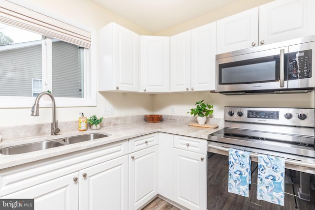 kitchen with white cabinetry, sink, light stone counters, and stainless steel appliances