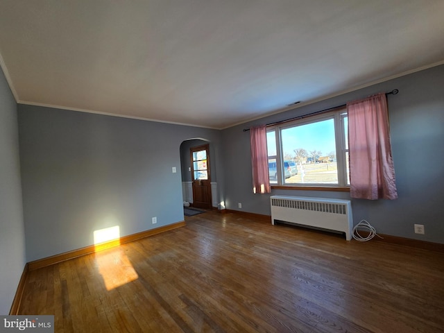 spare room with hardwood / wood-style flooring, crown molding, and radiator heating unit