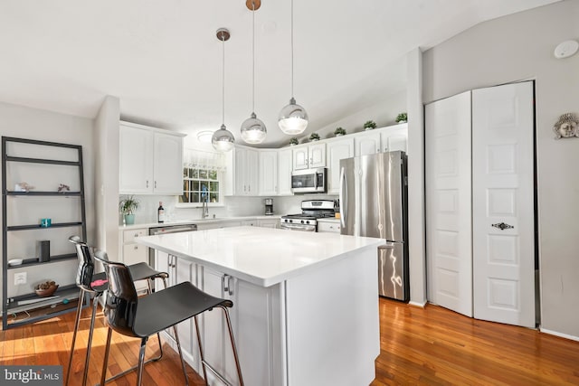 kitchen with a kitchen island, white cabinetry, a kitchen breakfast bar, hanging light fixtures, and stainless steel appliances