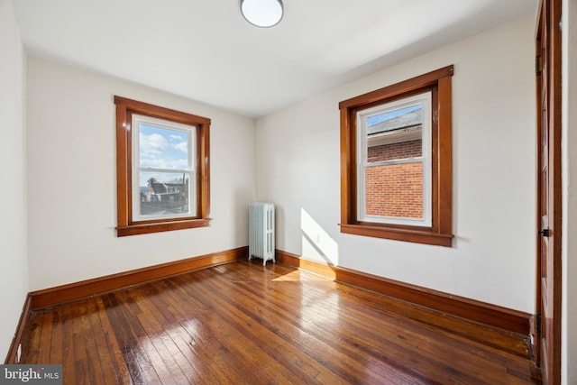 empty room with hardwood / wood-style floors and radiator heating unit