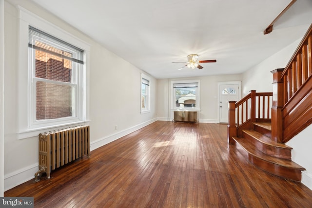 unfurnished living room with ceiling fan, dark wood-type flooring, and radiator heating unit